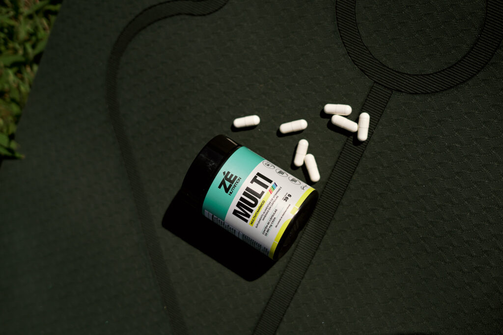uma embalagem do multivitamínico Zé Nutrition com as cápsulas dispostas ao lado sobre um tapete de yoga